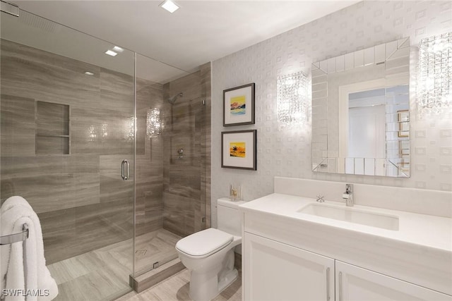 bathroom with toilet, a stall shower, vanity, and wallpapered walls