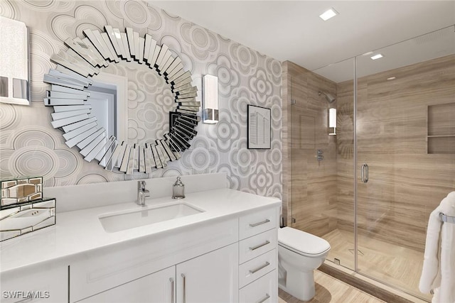 bathroom featuring vanity, toilet, wood finished floors, and a stall shower