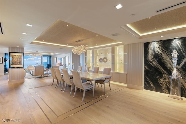 dining space featuring visible vents, recessed lighting, light wood-style floors, a raised ceiling, and a chandelier