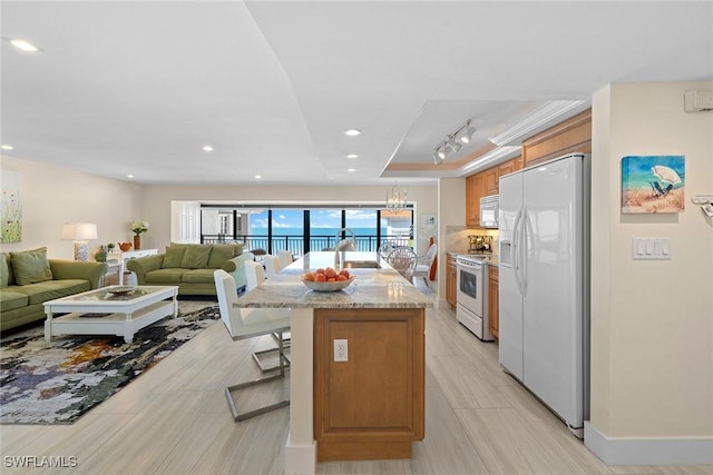 3333 Gulf Shore Blvd N Unit 4, Naples, FL 34103 - kitchen featuring brown cabinets, a breakfast bar, a center island with sink, open floor plan, and white appliances
