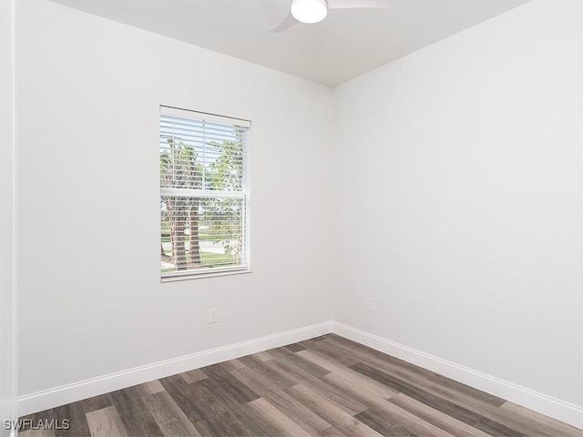 unfurnished room with dark wood-style floors, a ceiling fan, and baseboards