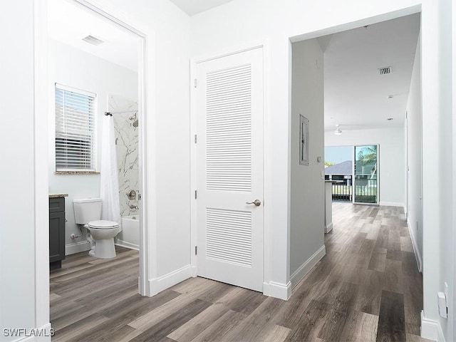 corridor featuring visible vents, baseboards, and wood finished floors