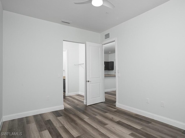 unfurnished bedroom with visible vents, a ceiling fan, dark wood-type flooring, and baseboards