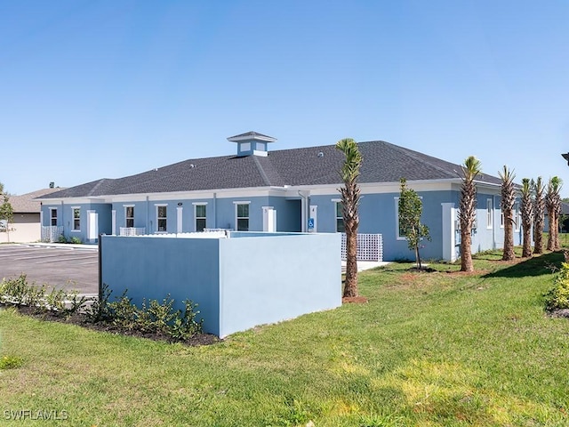 back of property with a lawn and stucco siding