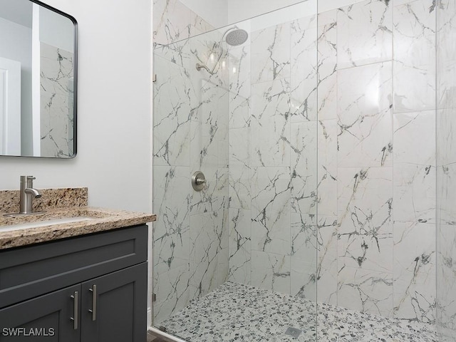 full bath with a marble finish shower and vanity