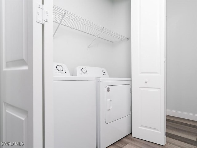 laundry area featuring washing machine and clothes dryer, laundry area, light wood finished floors, and baseboards