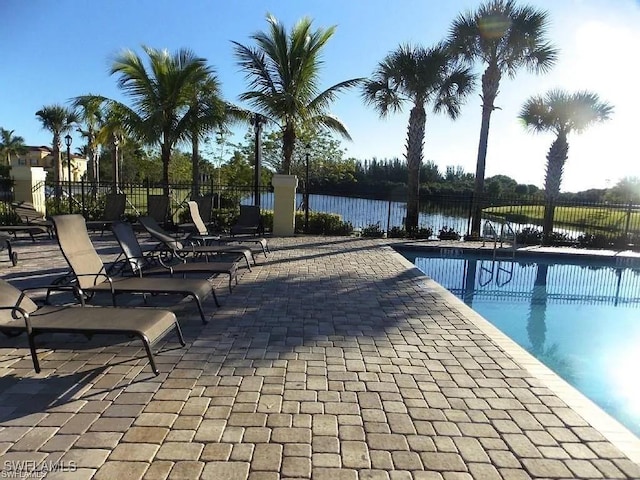 view of pool featuring a patio area, a fenced in pool, a water view, and fence