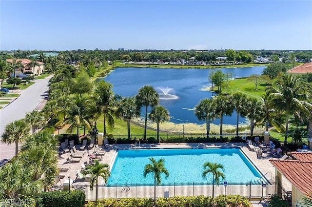 community pool featuring a patio area, fence, and a water view