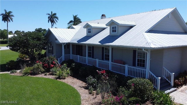 234 W Circle Dr, Clewiston, FL 33440 - view of front facade featuring a porch, metal roof, a front lawn, and a chimney