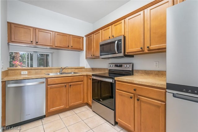 kitchen featuring light countertops, light tile patterned floors, a sink, appliances with stainless steel finishes, and brown cabinetry
