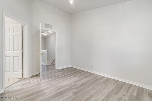 empty room with baseboards, ceiling fan, visible vents, and light wood finished floors