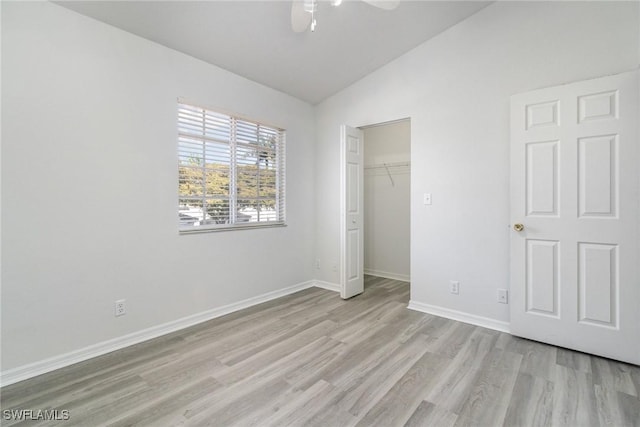 unfurnished bedroom with a closet, lofted ceiling, light wood-style flooring, baseboards, and ceiling fan