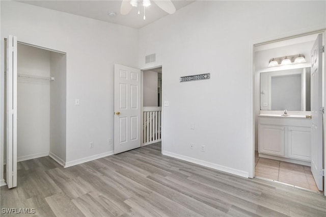 unfurnished bedroom featuring light wood-style flooring, a sink, baseboards, and visible vents