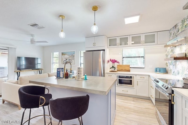 kitchen featuring white cabinets, a breakfast bar, visible vents, light countertops, and stainless steel appliances