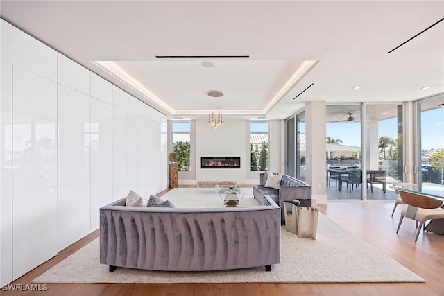 1165 8th St S Unit 202, Naples, FL 34102 - living area featuring expansive windows, a tray ceiling, a glass covered fireplace, and wood finished floors