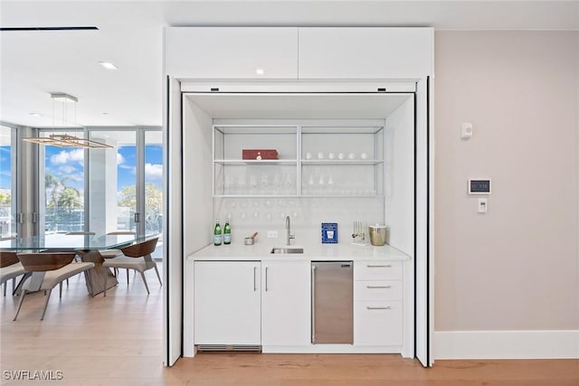 1165 8th St S Unit 202, Naples, FL 34102 - bar with a sink, a wall of windows, indoor wet bar, baseboards, and light wood-style floors