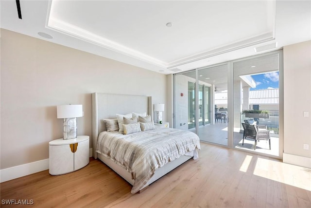 1165 8th St S Unit 202, Naples, FL 34102 - bedroom featuring floor to ceiling windows, a raised ceiling, access to outside, light wood-type flooring, and baseboards