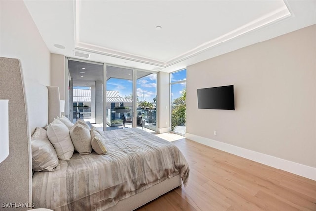 1165 8th St S Unit 202, Naples, FL 34102 - bedroom featuring a tray ceiling, access to exterior, floor to ceiling windows, wood finished floors, and baseboards