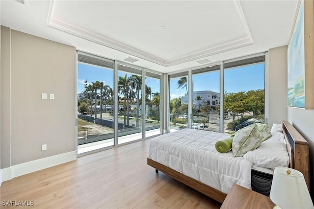1165 8th St S Unit 202, Naples, FL 34102 - bedroom featuring floor to ceiling windows, wood finished floors, access to exterior, multiple windows, and a tray ceiling