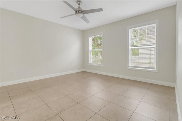 spare room featuring light tile patterned flooring, a ceiling fan, and baseboards