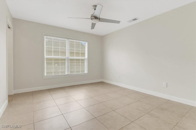 spare room featuring light tile patterned floors, visible vents, a ceiling fan, and baseboards