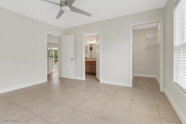 unfurnished bedroom featuring multiple windows, a walk in closet, and baseboards