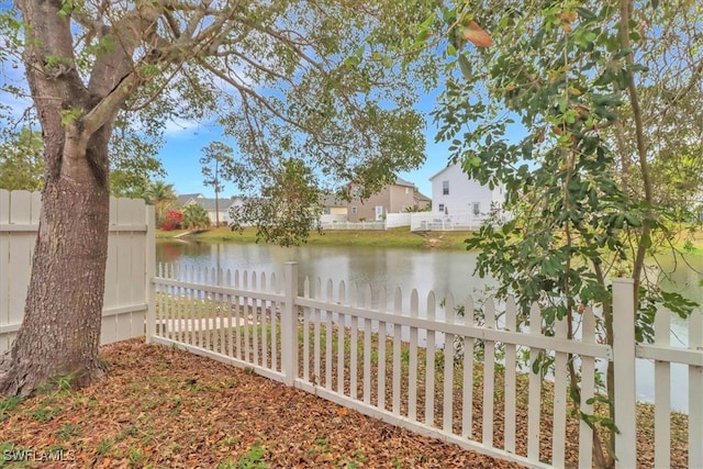 view of yard featuring fence, a water view, and a residential view