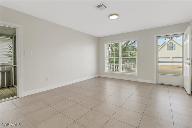 unfurnished room with light tile patterned flooring, visible vents, and baseboards