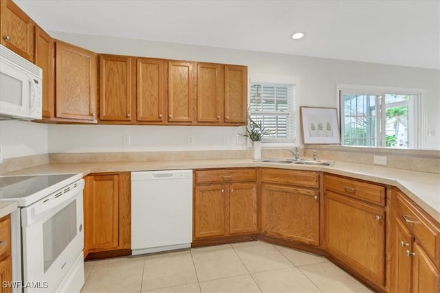 kitchen featuring brown cabinetry, white appliances, light countertops, and a sink