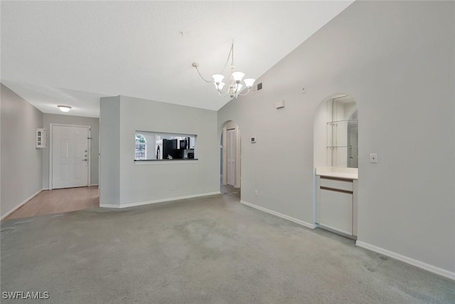 529 Mardel Dr Unit 311, Naples, FL 34104 - unfurnished living room featuring arched walkways, light carpet, a chandelier, baseboards, and a towering ceiling