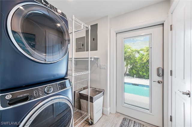 clothes washing area with electric panel, wood finished floors, laundry area, and stacked washer / dryer