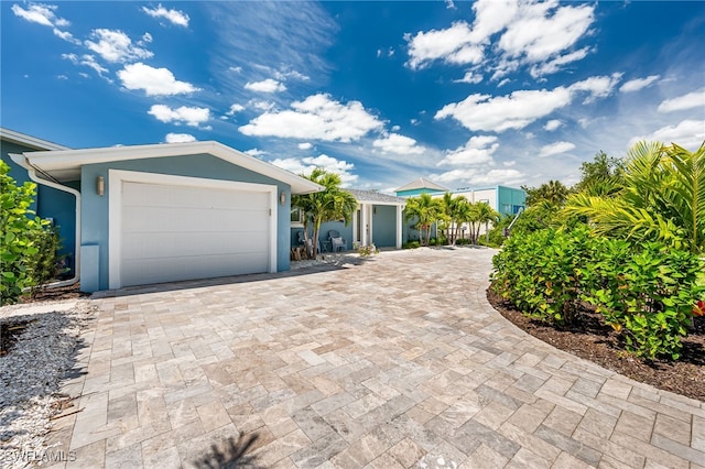 view of front facade featuring a garage, decorative driveway, and stucco siding
