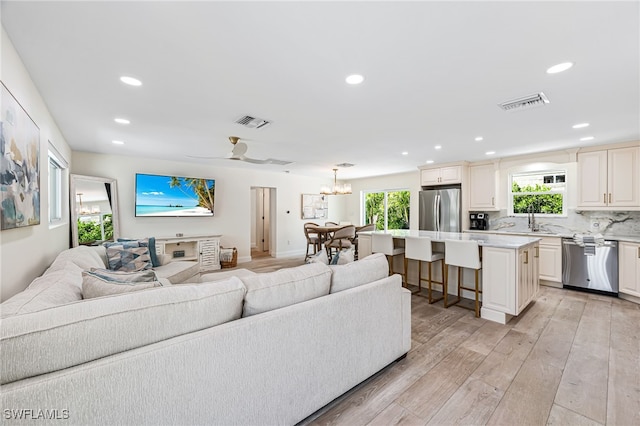 living room with a wealth of natural light, a notable chandelier, recessed lighting, and light wood-type flooring