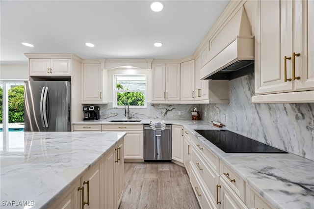 kitchen with custom exhaust hood, light wood-style flooring, a sink, decorative backsplash, and stainless steel appliances