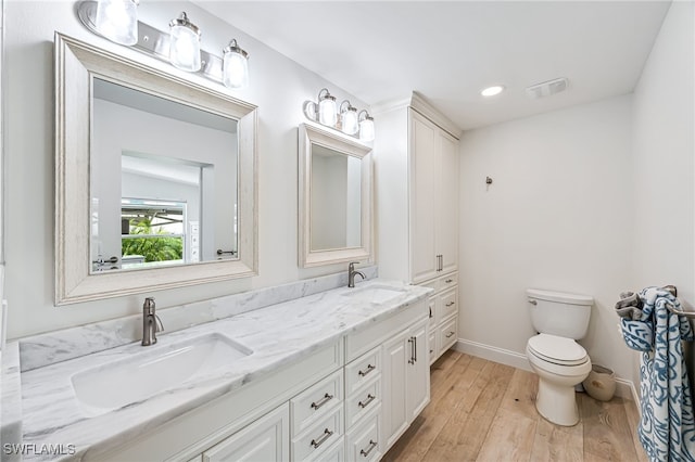 bathroom with toilet, wood finished floors, baseboards, and a sink