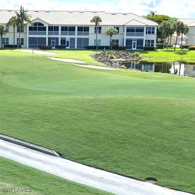 view of home's community featuring a yard, a water view, and golf course view
