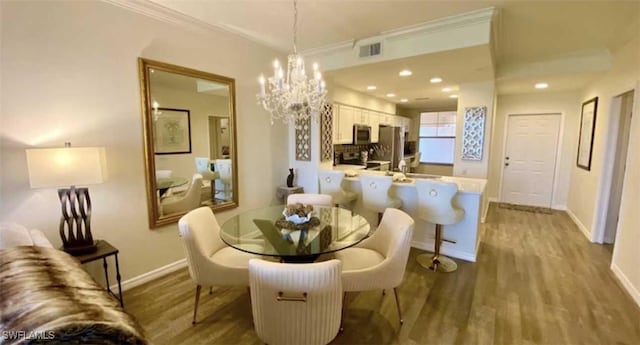 dining room featuring visible vents, baseboards, an inviting chandelier, and wood finished floors