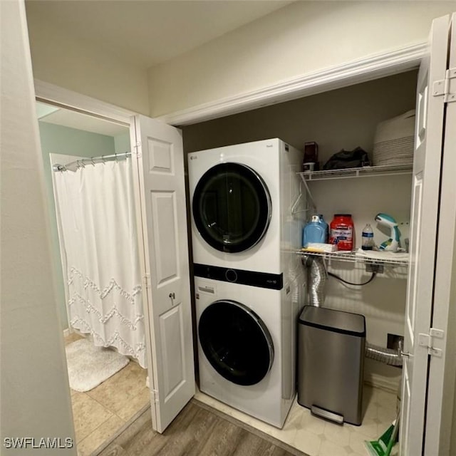laundry room with laundry area, stacked washer / drying machine, and light wood-type flooring