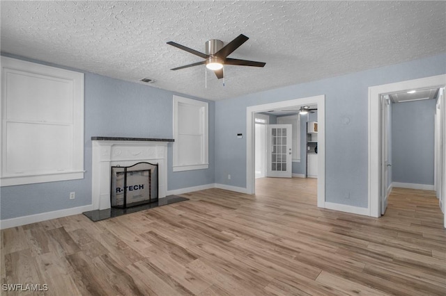 290 Granada Blvd, Fort Myers, FL 33905 - unfurnished living room featuring a fireplace with raised hearth, a textured ceiling, light wood finished floors, visible vents, and a ceiling fan
