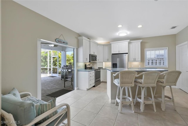 41 5th St, Bonita Springs, FL 34134 - kitchen with stainless steel appliances, white cabinets, a kitchen bar, light tile patterned floors, and recessed lighting