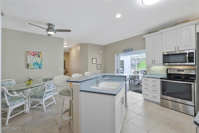 41 5th St, Bonita Springs, FL 34134 - kitchen featuring appliances with stainless steel finishes, light tile patterned flooring, ceiling fan, a breakfast bar, and an island with sink