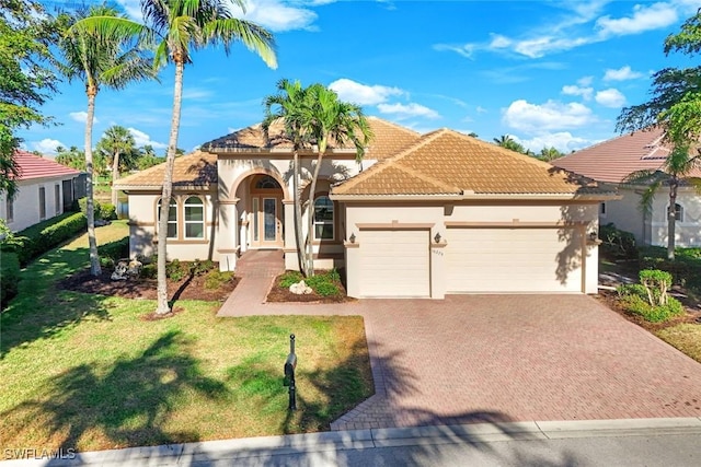 mediterranean / spanish-style house featuring stucco siding, a tiled roof, decorative driveway, and a garage