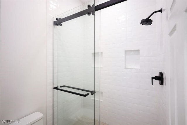 bathroom with a shower stall and toilet