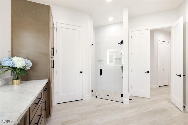 interior space featuring recessed lighting, a shower stall, vanity, and wood finished floors