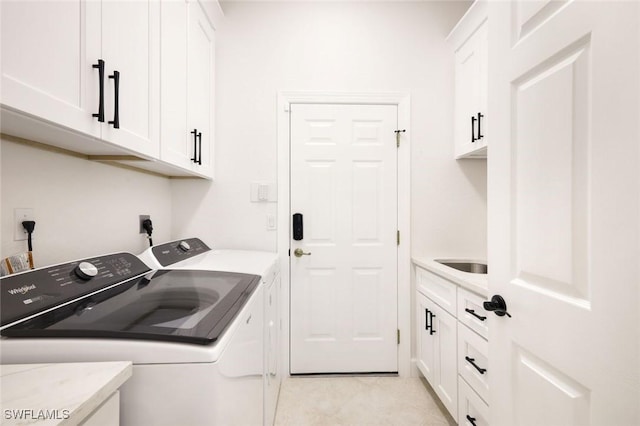 laundry area featuring cabinet space, light tile patterned flooring, washing machine and dryer, and a sink