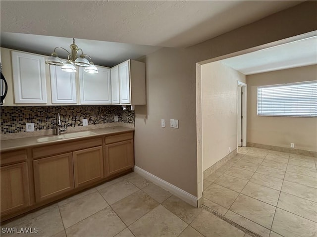 1434 Alhambra Dr, Fort Myers, FL 33901 - kitchen with light countertops, light tile patterned floors, a sink, decorative backsplash, and a notable chandelier