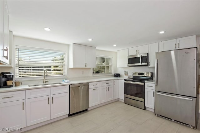 kitchen with light countertops, a sink, stainless steel appliances, white cabinets, and recessed lighting
