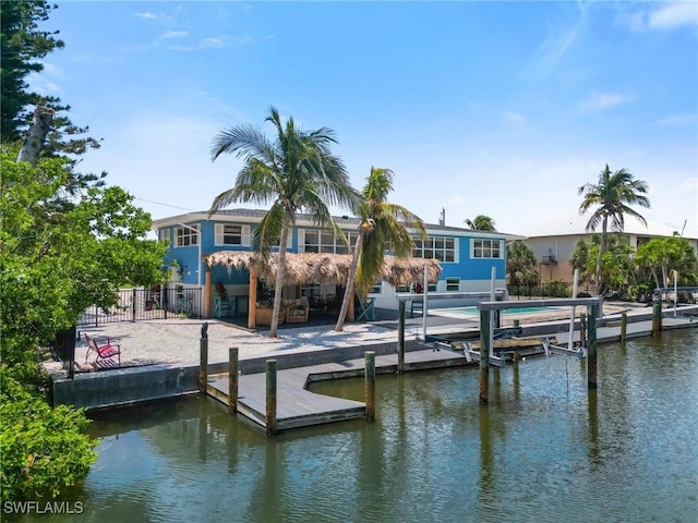 dock area with boat lift, a water view, and fence