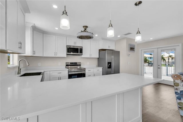 kitchen featuring light countertops, french doors, a sink, a peninsula, and appliances with stainless steel finishes