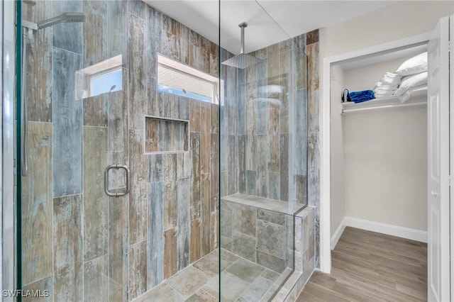 bathroom with a spacious closet, baseboards, and a shower stall